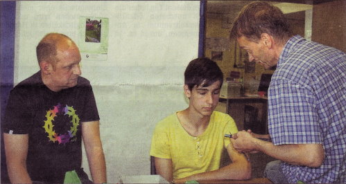 Die Mitarbeiter der Lebenshilfe Dan (links) und Dieter (rechts) erklären Schüler David die Arbeitsabläufe der Industriemontage.